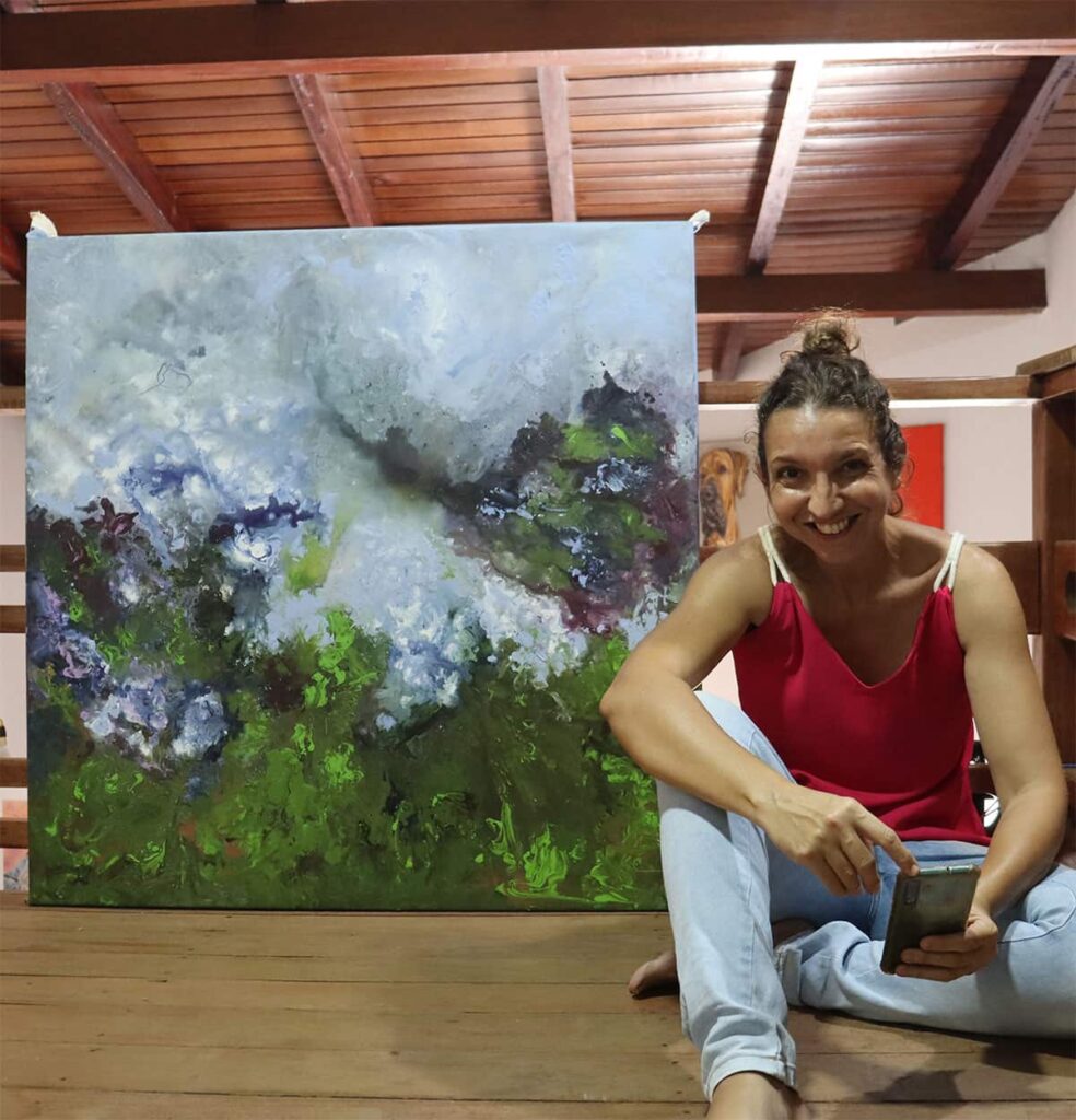Carolina Rocha, artista plástica, ao lado de pintura abstrata em seu estúdio.
